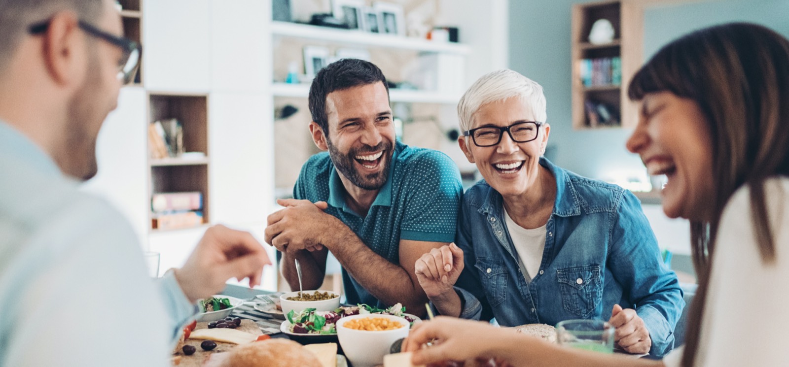 a group of adults sitting at a tablet with food