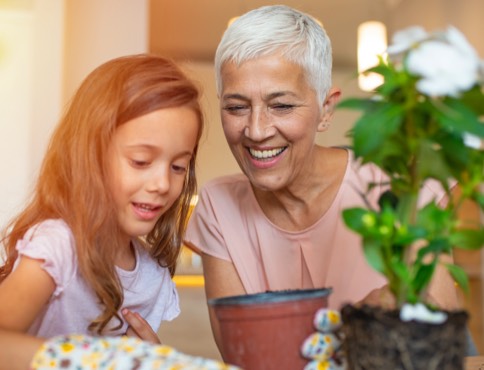 an adult woman planting flowers with a young girl